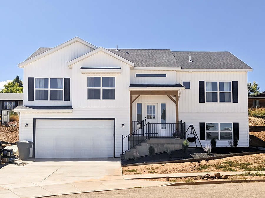 A split level two story new home with a classic farmhouse style: white siding with black accents by Smart Dwellings in Southwest Wyoming 